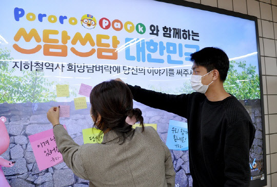 6일 서울 지하철 6호선 공덕역 대합실에서 진행된 뽀로로파크와 함께하는 대국민 코로나19 극복 응원 캠페인 '쓰담쓰담 대한민국'에서 시민들이 응원 메시지를 광고판에 붙이고 있다.